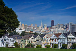 Řadové domky s panoramatem města v pozadí. Vidět je mrakodrap Transamerica Pyramid a vedle něj budova Bank of America